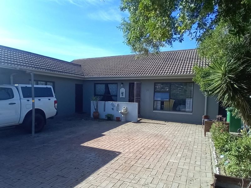 Front elevation of the house featuring a paved driveway, tiled roof, and secure entrance with aluminium window frames.