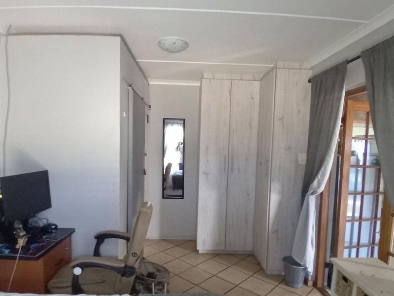 Bedroom featuring built-in cupboards, tiled flooring, and a sliding door providing access to an adjacent space.