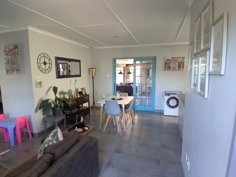 Open plan living and dining area featuring tiled flooring and blue-framed french doors leading to an adjacent space.