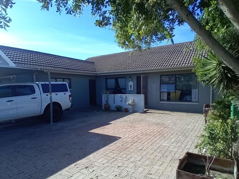 Front exterior view of a single-story house featuring a paved driveway, carport, and tiled roof.