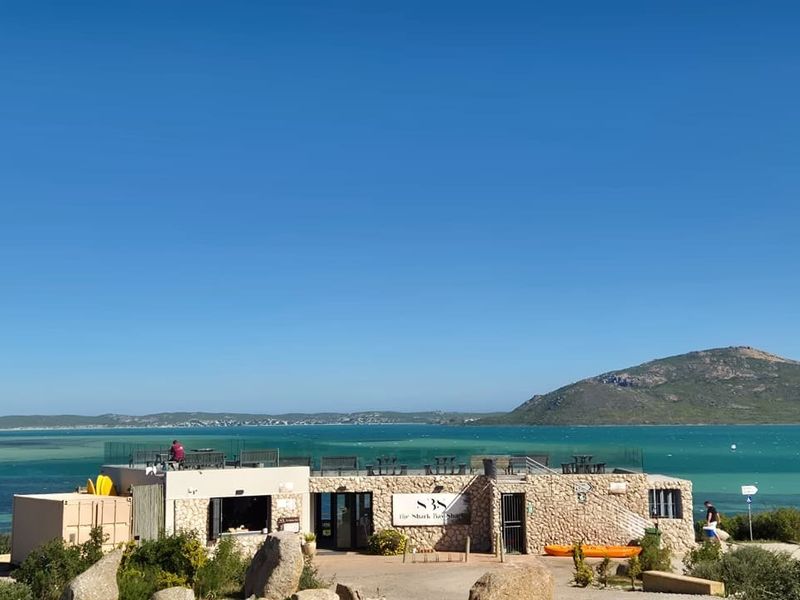 A coastal commercial property featuring stone cladding and a rooftop terrace overlooking the ocean and surrounding landscape.