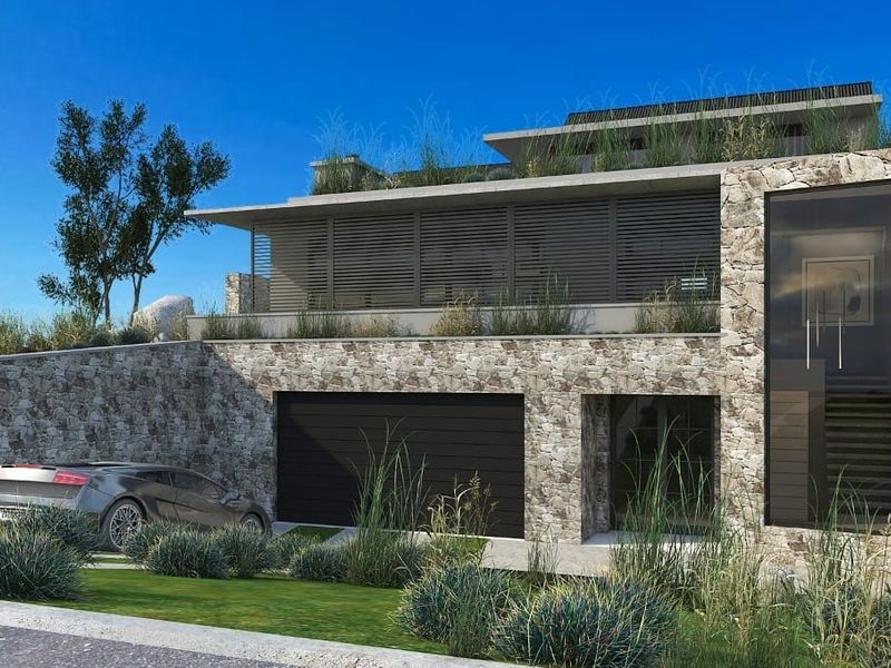 Modern architectural residence featuring natural stone cladding, integrated garage, and contemporary louvred facade elements set within a landscaped environment.