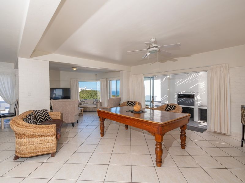 Spacious open-plan living area featuring tiled flooring, a ceiling fan, and a built-in fireplace with direct access to an outdoor patio area.