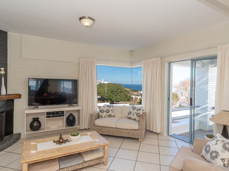 Bright living room featuring a brick fireplace, tiled flooring, and large sliding doors opening to a patio with scenic coastal views.
