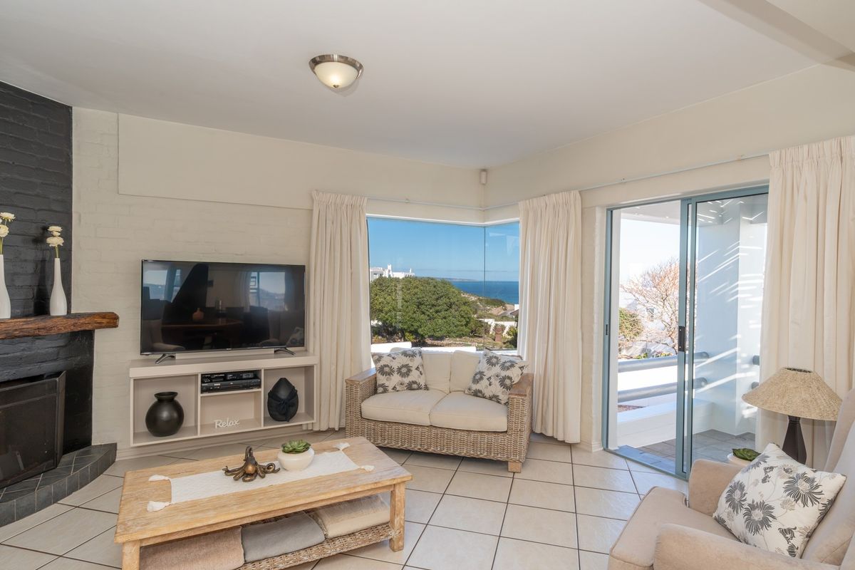 Bright living room featuring a brick fireplace, tiled flooring, and large sliding doors opening to a patio with scenic coastal views.