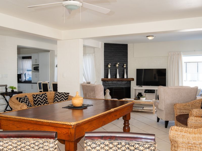 Spacious open-plan living and dining area featuring a prominent black brick fireplace, tiled flooring, and a seamless transition to the adjacent kitchen space.