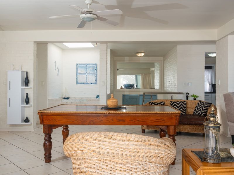 Spacious open-plan living area featuring painted brick walls, tiled flooring, a ceiling fan, and a skylight, offering a bright and versatile layout.