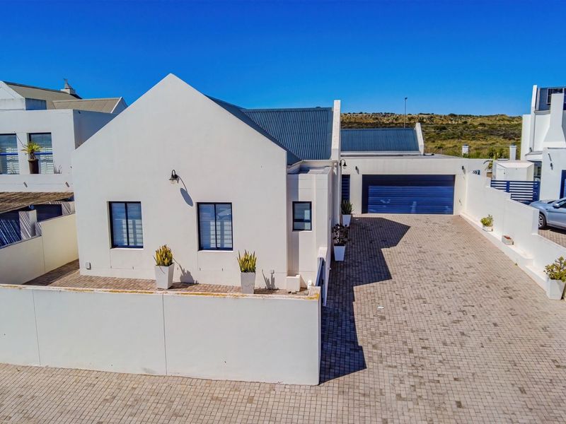Aerial view of a modern white house featuring a paved driveway, enclosed boundary wall, and a secure garage.