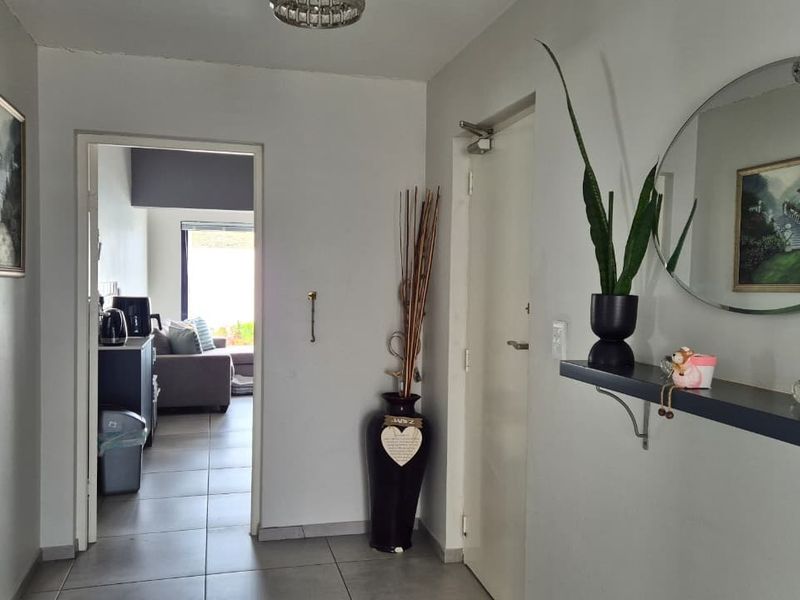 A clean and functional hallway featuring neutral tiled flooring and direct access to the adjacent living area.