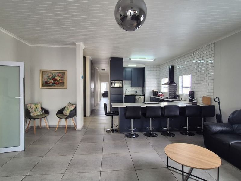 Spacious open-plan living area featuring a modern kitchen with a central island, subway tile backsplash, and neutral tiled flooring throughout.