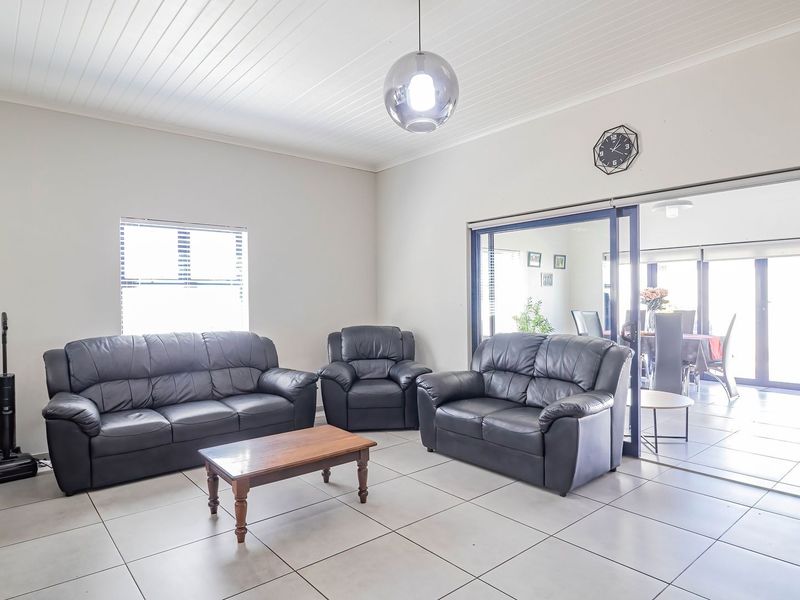 Spacious living area featuring neutral tiled flooring, a classic tongue and groove ceiling, and large sliding glass doors that provide access to the adjoining space.