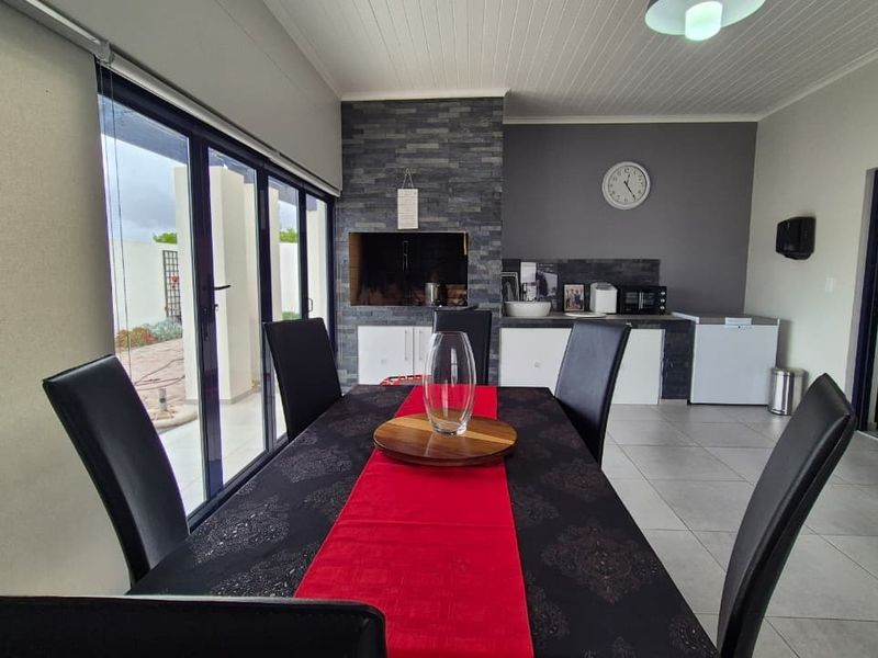 Covered patio area featuring a built-in braai with stone cladding, tiled flooring, and sliding doors leading to the exterior.