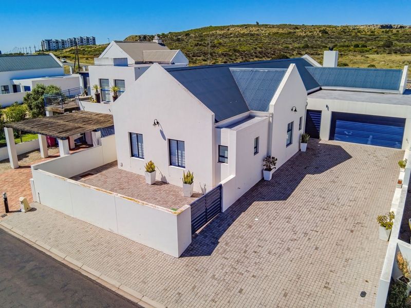 Aerial view of a modern residential property featuring a paved driveway, double garage, and a private courtyard with a pergola.