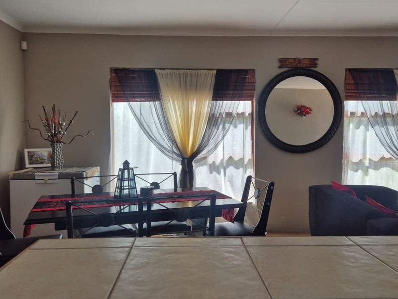 Open plan living and dining area featuring a tiled breakfast counter and neutral wall finishes.