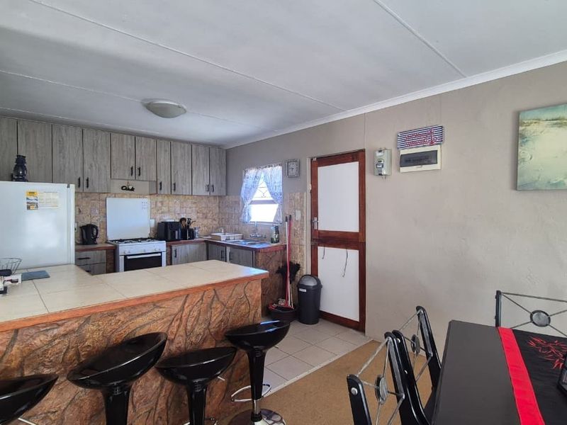 Open plan kitchen and dining area featuring a tiled breakfast counter, built-in cabinetry, gas stove, and direct access to the exterior.