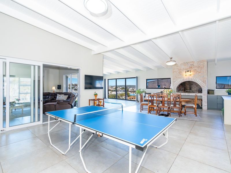 Spacious open-plan living area featuring a brick fireplace, exposed beam ceiling, and large sliding doors leading to an outdoor view.
