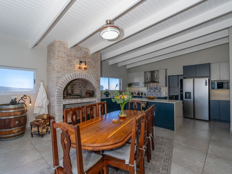 Spacious open-plan living and kitchen area featuring a prominent brick fireplace, exposed beam ceilings, and modern cabinetry with a central island.
