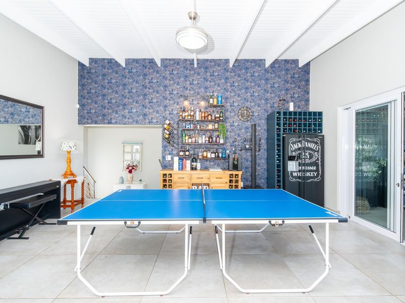 Spacious entertainment area featuring a built-in bar, wine storage, exposed beam ceiling, and large sliding glass doors leading to the exterior.