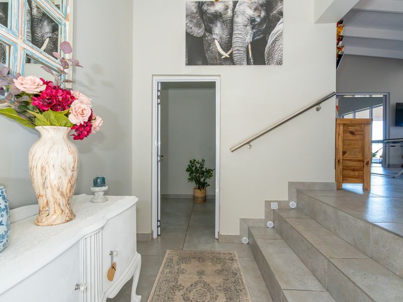 Welcoming entrance hall featuring tiled flooring, a staircase with a modern stainless steel handrail, and integrated stair lighting leading to an adjacent room.