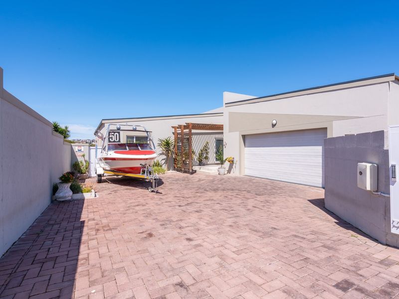 Front exterior view featuring a paved driveway, double garage, and a timber pergola entrance.