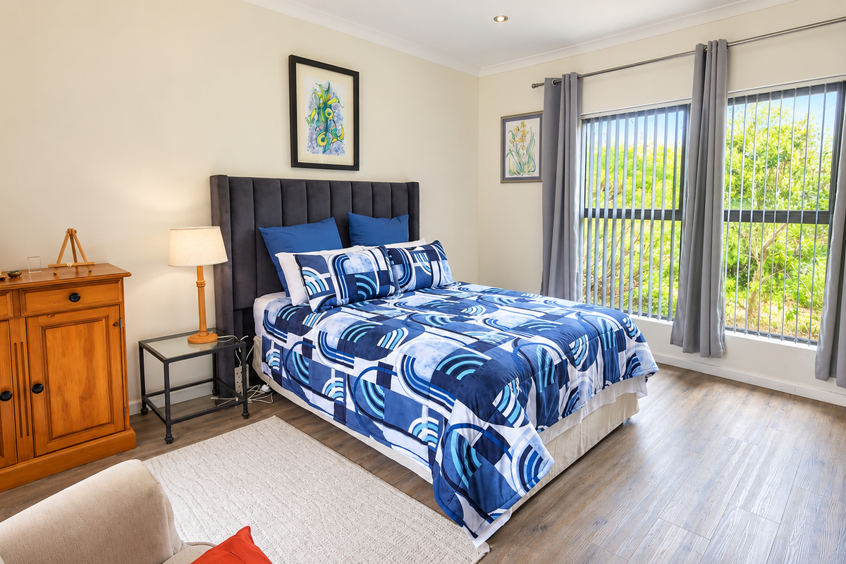 A well-maintained bedroom featuring laminate flooring, recessed lighting, and large windows with vertical blinds, offering a bright and comfortable living space.