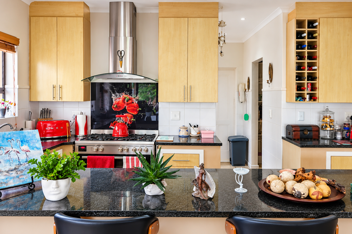 A well-maintained kitchen featuring light wood cabinetry, granite countertops, a stainless steel gas hob with extractor, and a dedicated built-in wine rack.