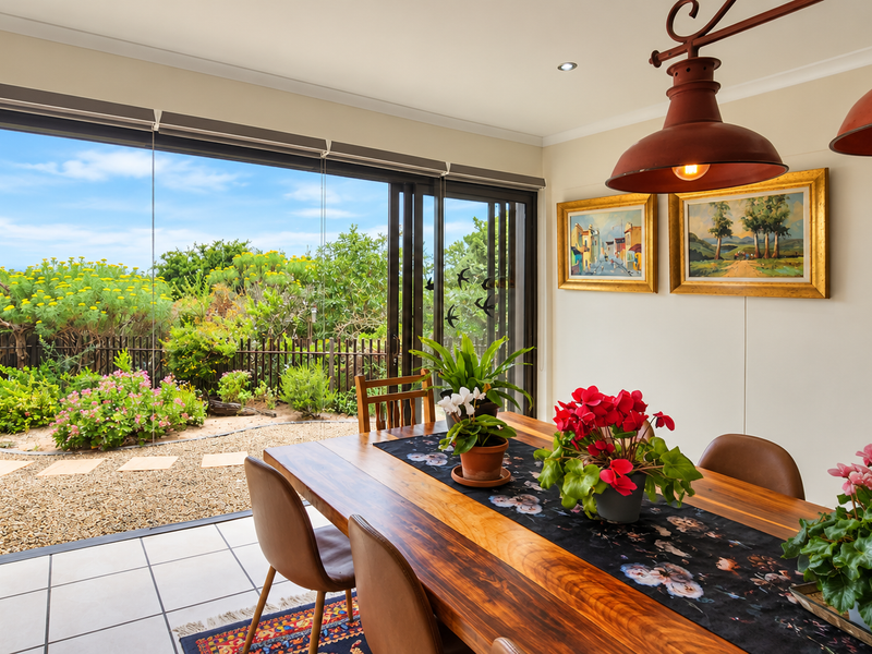 Bright dining area featuring large sliding glass doors that open onto a landscaped garden, creating a seamless indoor-outdoor flow.