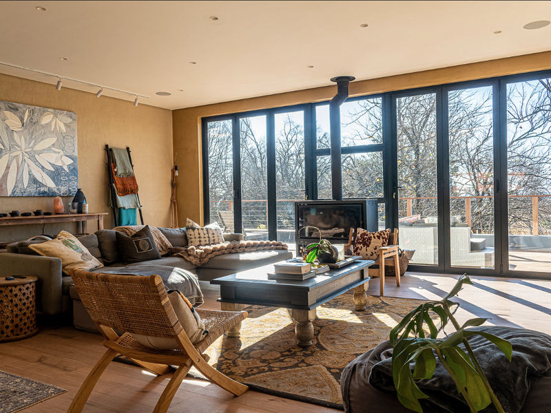 Spacious living room featuring a modern wood-burning fireplace, timber flooring, and large bi-fold doors that open to an outdoor deck area.