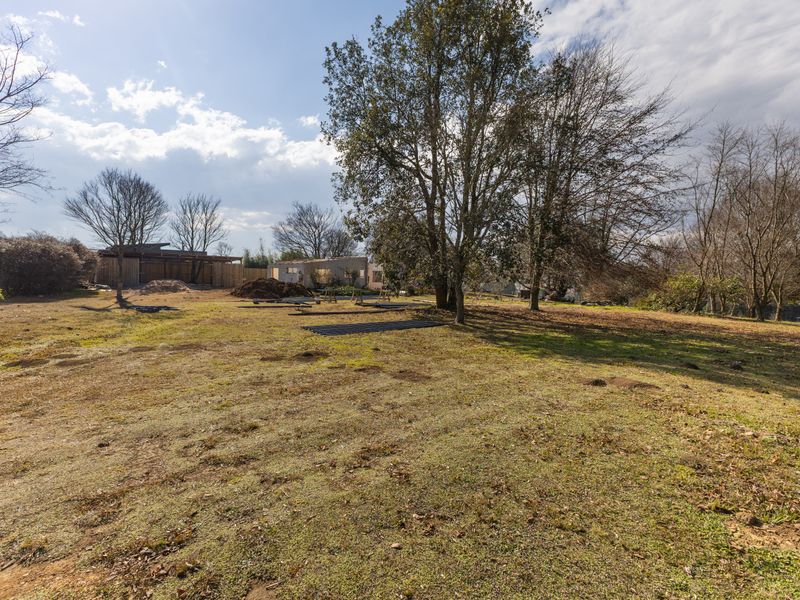 A spacious residential plot featuring mature trees and open, cleared land, offering potential for future development or landscaping.