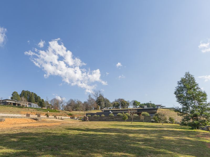A spacious, well-maintained residential plot featuring landscaped lawns and stone retaining walls, set within a scenic estate environment.