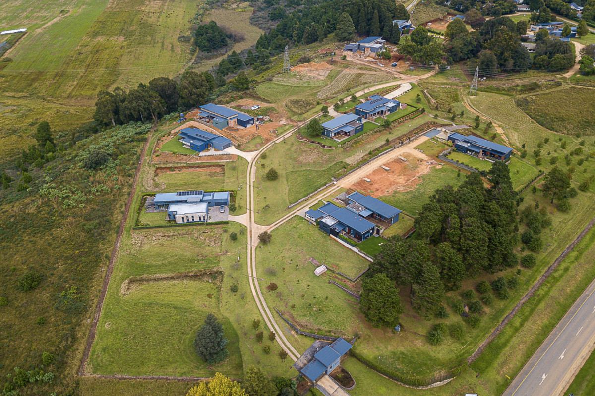 An aerial view of a residential estate development featuring multiple modern homes, paved access roads, and landscaped grounds set within a rural landscape.