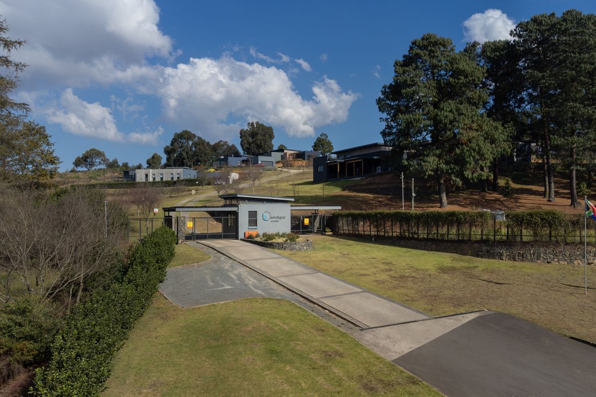 Aerial view of the secure estate entrance featuring a modern gatehouse, paved driveway, and well-maintained landscaped grounds.