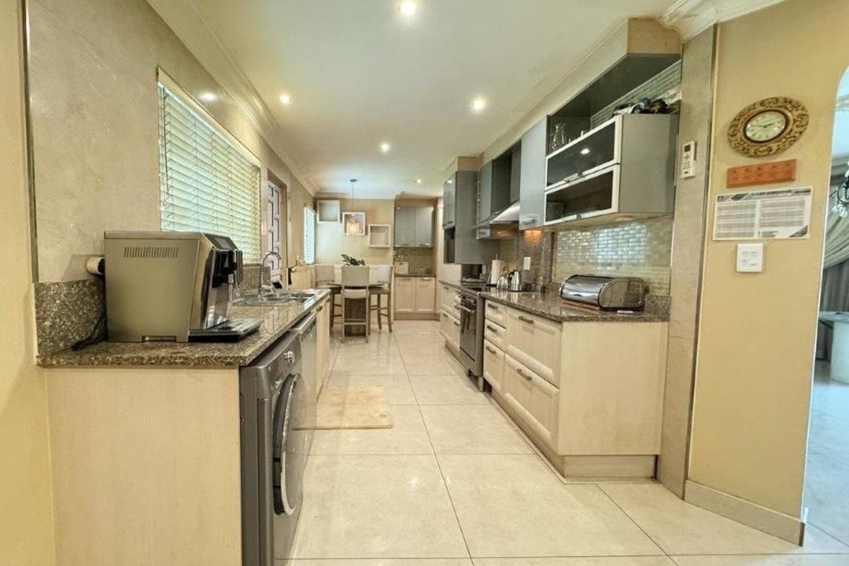 A functional galley-style kitchen featuring granite countertops, ample built-in cabinetry, tiled flooring, and recessed lighting, offering a practical layout for daily meal preparation.