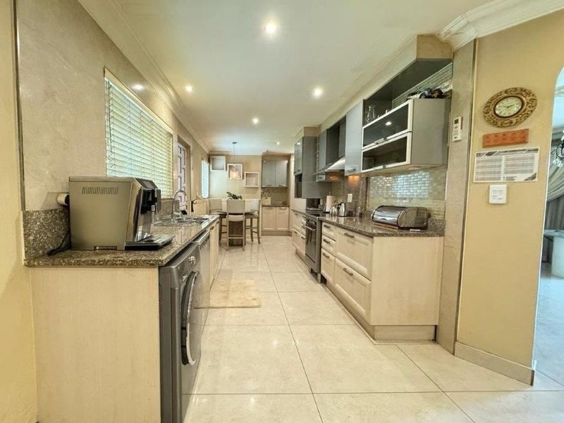A functional galley-style kitchen featuring granite countertops, ample built-in cabinetry, tiled flooring, and recessed lighting, offering a practical layout for daily meal preparation.