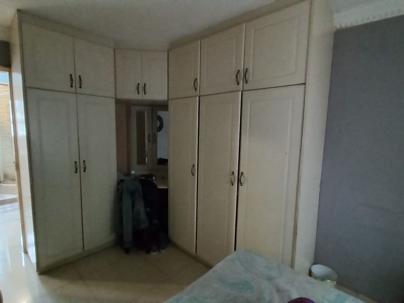 A bedroom featuring extensive built-in cabinetry with an integrated vanity section and decorative ceiling coving.