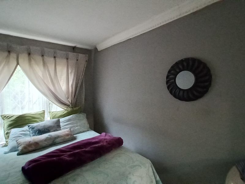A cozy bedroom featuring decorative ceiling cornicing and a window fitted with a security gate.