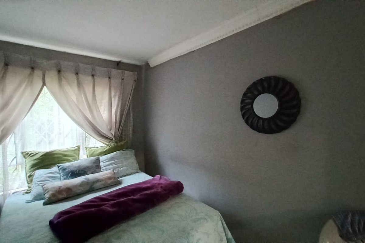 A cozy bedroom featuring decorative ceiling cornicing and a window fitted with a security gate.