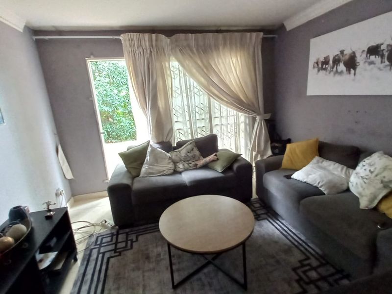 A comfortable living room featuring a sliding glass door with security gate, providing access to the exterior and natural light.