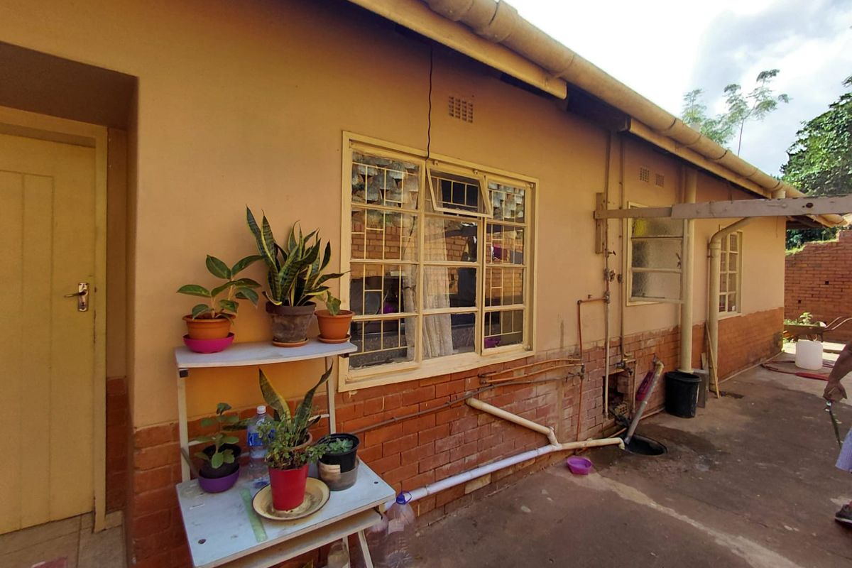Rear exterior view of the property featuring brick wall construction, steel window frames, and visible external plumbing infrastructure.