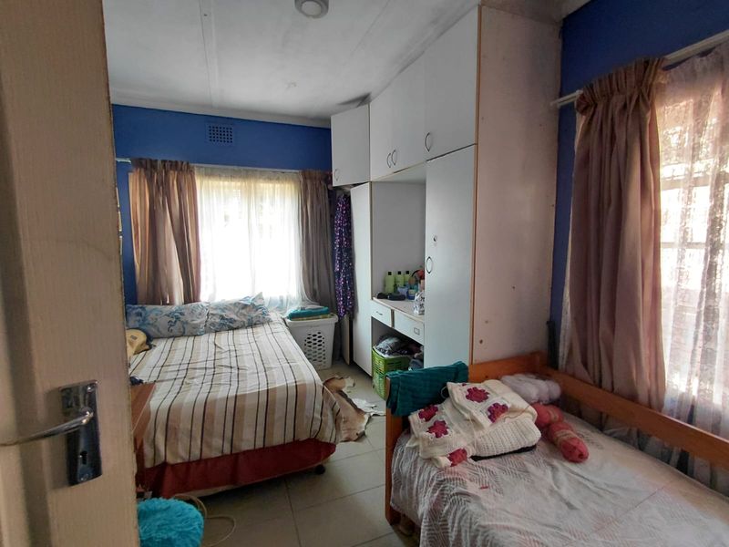 A bedroom featuring built-in cupboards and tiled flooring, offering functional storage space with potential for cosmetic updates to enhance the room's appeal.