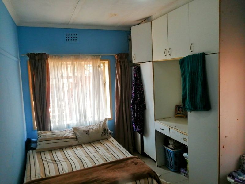 A bedroom featuring built-in cupboards and a vanity unit, with visible ceiling water staining requiring attention.