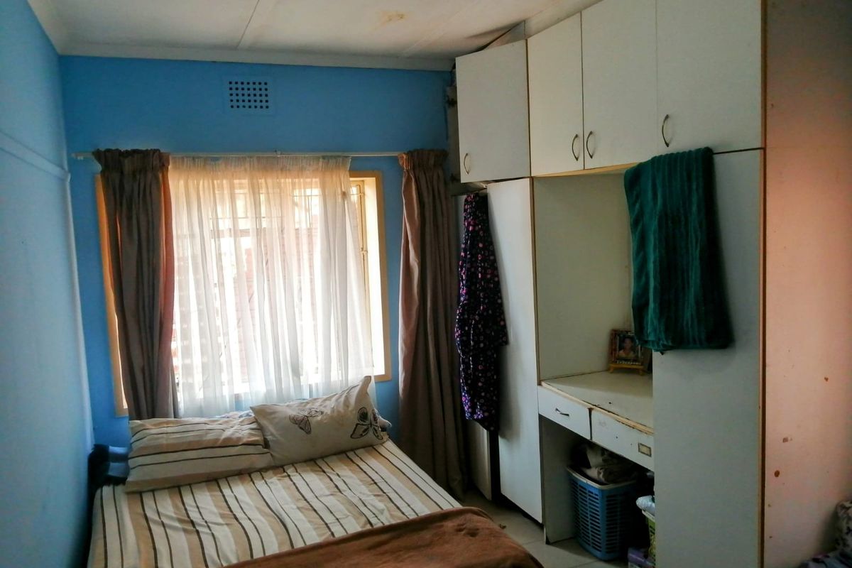A bedroom featuring built-in cupboards and a vanity unit, with visible ceiling water staining requiring attention.