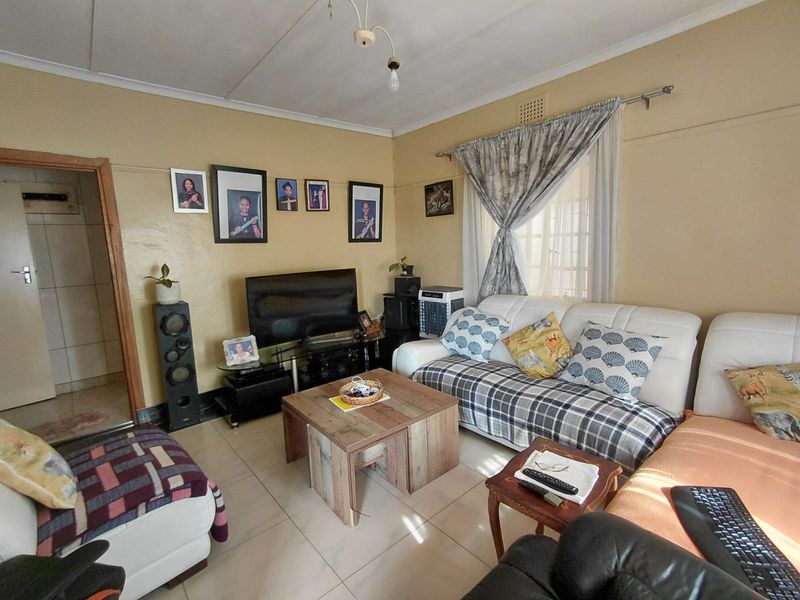 A living room featuring tiled flooring and standard ceiling finishes, offering a functional space that could benefit from cosmetic updates and modern styling.