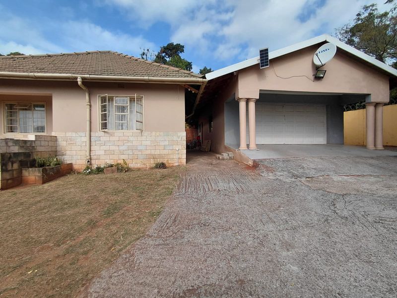 Front exterior view of the house featuring a concrete driveway, garage, and stone-clad facade with tiled roofing.