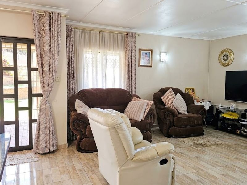 A well-maintained living room featuring tiled flooring, wall-mounted air conditioning, and a sliding glass door providing direct access to the outdoor patio area.
