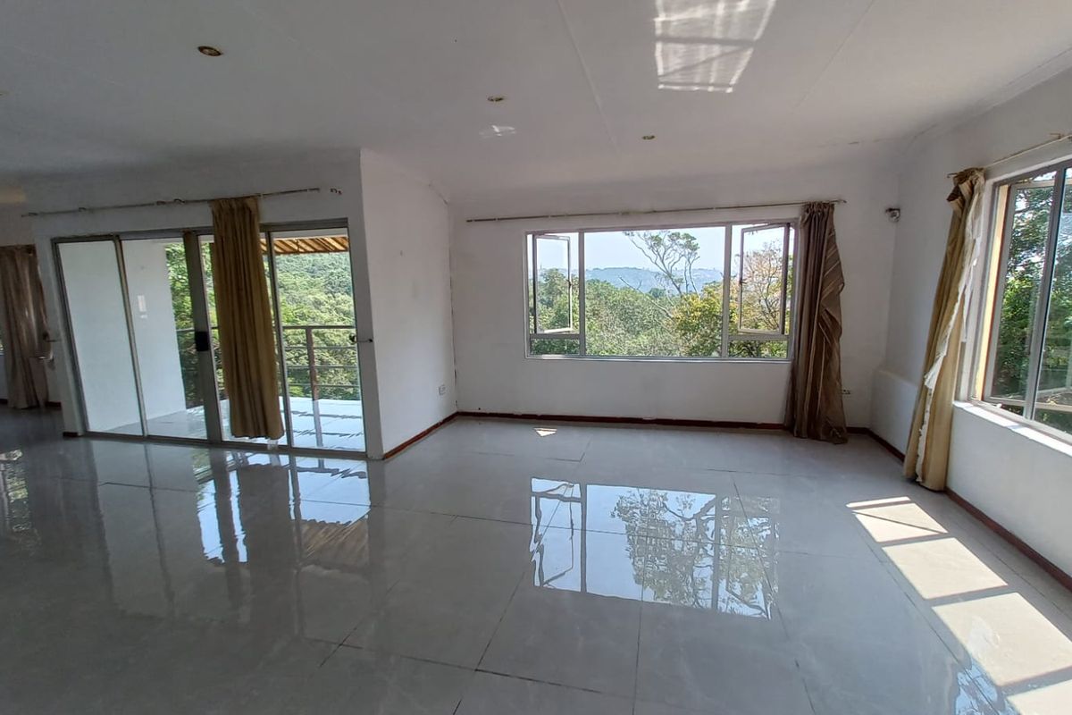 Spacious, light-filled living area featuring large windows, sliding glass doors leading to a balcony, and polished tiled flooring with scenic views.