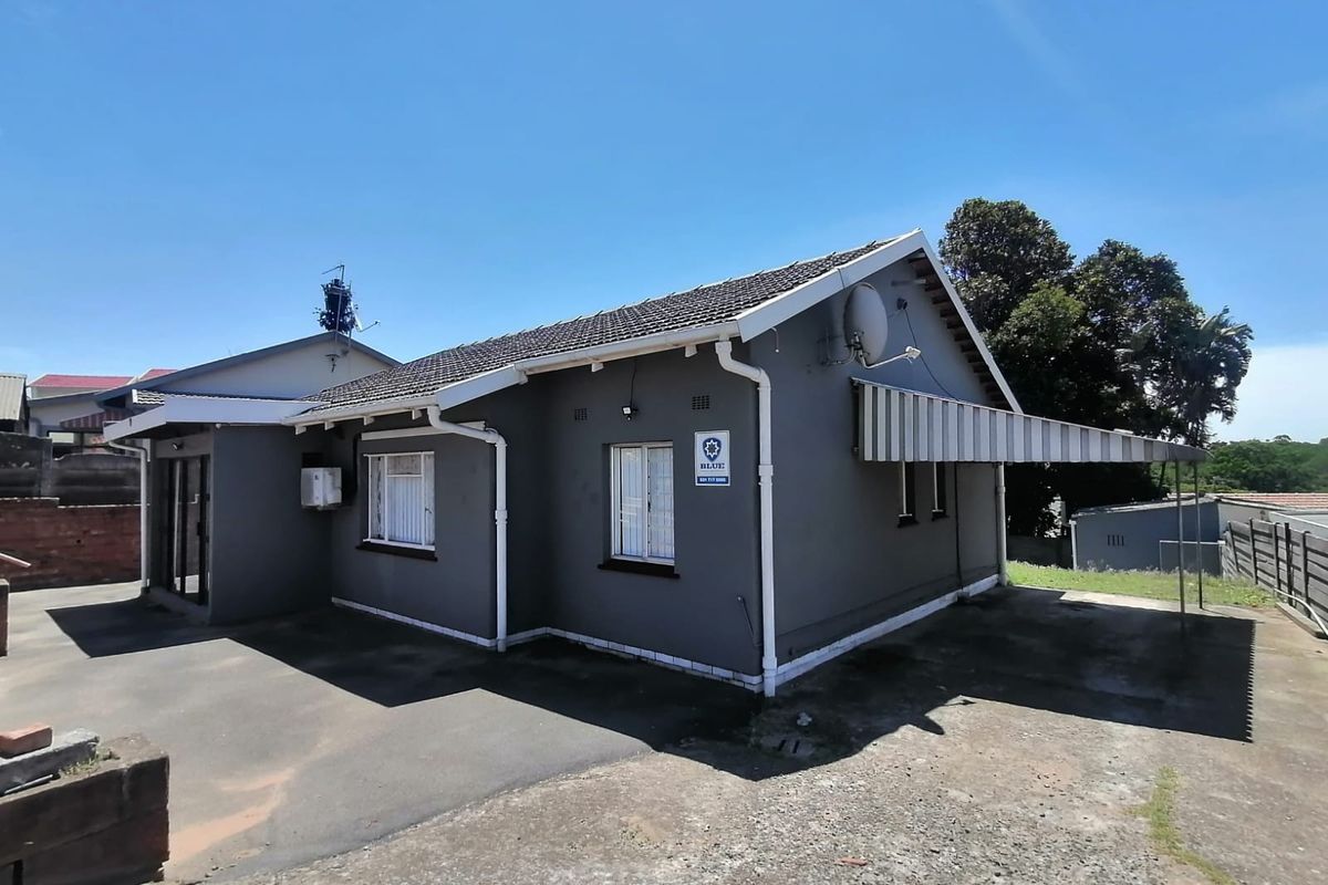 Rear view of the property featuring a tiled roof, asphalt driveway, and a fixed side awning.