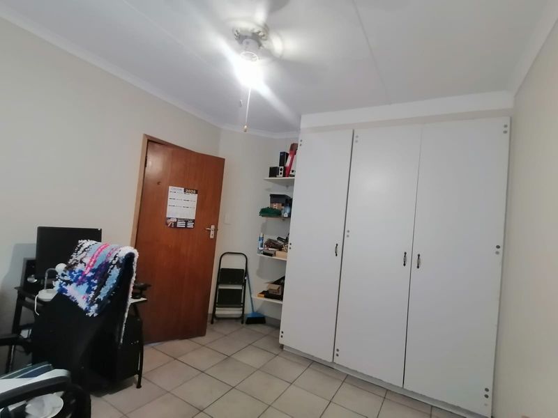 A functional bedroom featuring tiled flooring, built-in wardrobes, and integrated shelving, offering practical storage space within the townhouse.