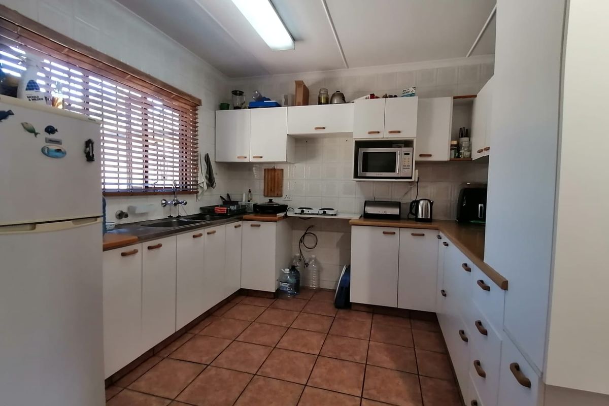 A functional kitchen featuring white cabinetry, tiled backsplash, tiled flooring, and a double sink, offering a practical layout for daily meal preparation.