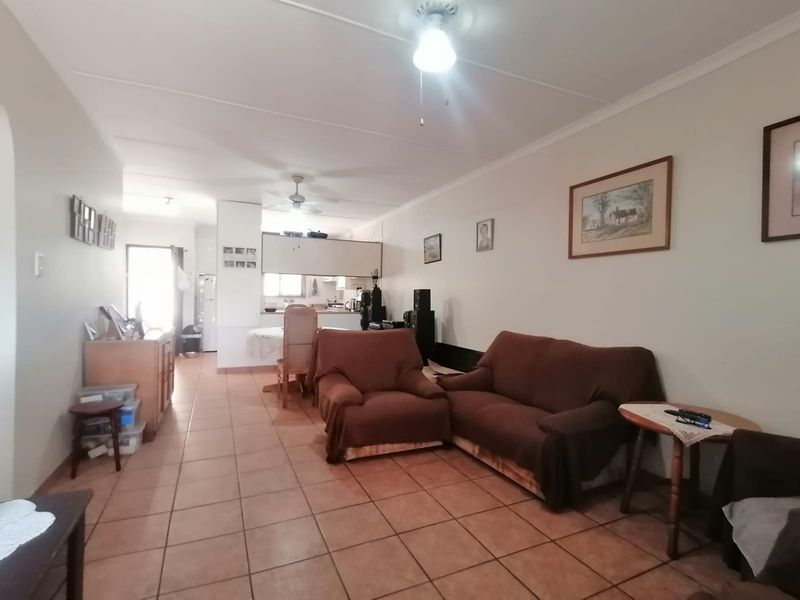 An open-plan living and kitchen area featuring tiled flooring and ceiling fans, offering a functional layout with direct access to the kitchen space.